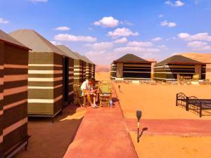 un hombre sentado en una mesa fuera de un edificio en Bedouin Tours Camp en Wadi Rum