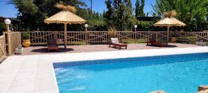 a swimming pool with two umbrellas and two chairs at Rincón Azul in San Rafael