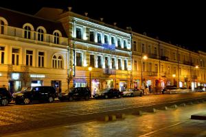 a city street at night with cars parked in front of buildings at King David Hotel in Tbilisi City