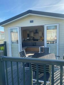a screened in porch with a table and chairs on a deck at Modern 3 bedroom caravan near the beach in Walton-on-the-Naze