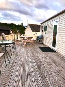 una terraza de madera con mesa y mesa de picnic en Summer Breeze, en Aviemore