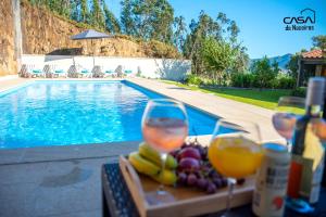 zwei Gläser Wein und Obst auf einem Tisch in der Nähe eines Swimmingpools in der Unterkunft Casa de Naceiros - Ponte de Lima in Viana do Castelo