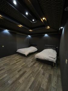 2 letti in una camera nera con pavimenti in legno di منتجع ريف العلا a Al Ula