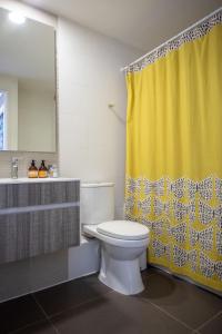 baño con aseo y cortina de ducha amarilla en Depto con Vista soñada y tinaja a pasos del centro en Puerto Varas