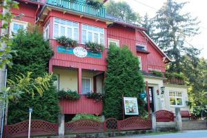 un edificio rojo con plantas a su lado en Pension Villa Irene en Kurort Gohrisch