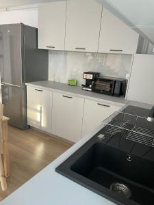 een keuken met witte kasten en een zwarte wastafel bij Penthouse DH Apartments in Oradea