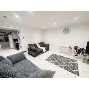 a living room with a couch and a clock on the wall at Cosy & Spacious Lodge Dartford in Kent