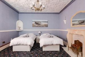 a blue bedroom with two beds and a chandelier at Beautiful 'Mayfield' Villa with private pool! in Manchester