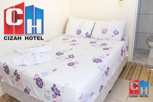a bedroom with a bed with purple flowers on it at Cizah Hotel in Faxinal