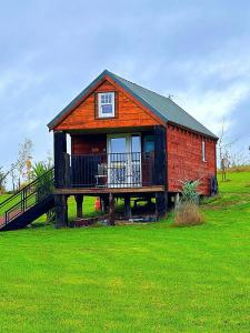 a small house with a deck on a green field at Lake View Lodges in Long Melford