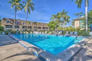 a swimming pool in front of a building with palm trees at Condo with Pool Access Walk to Shopping and Beach! in Naples