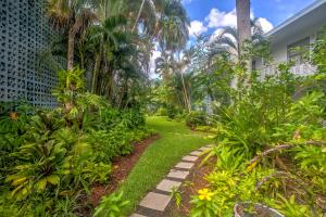 a path through a garden with palm trees and plants at Condo with Pool Access Walk to Shopping and Beach! in Naples