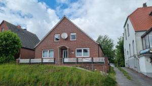 a brick house with a white fence in front of it at Nordseeblick 1 - XXL Ferienwohnung in Carolinensiel