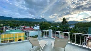a balcony with two chairs and a view of a city at Victoria's Bed & Breakfast in Puerto Galera