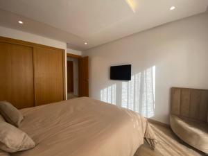a bedroom with a bed and a television on the wall at CORNICHE CASABLANCA - SUBLIME F2 NEUF in Casablanca
