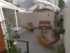 un patio con sillas, mesas y una sombrilla en ESPERIA B&B, en Oliveri