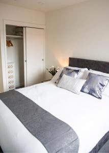 um quarto com uma grande cama branca e 2 almofadas em Chi-Amore- 1 bed apartment-Bedford Town (Free Gym) em Bedford