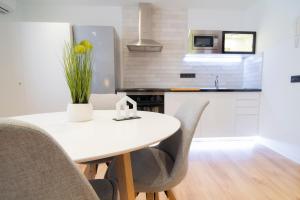 kuchnia z białym stołem z krzesłami i wazonem kwiatów w obiekcie Laguna Home & Suites w mieście La Laguna +37 zdjęć