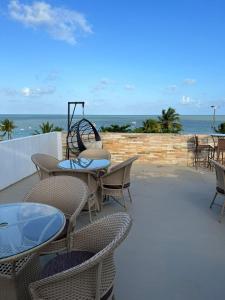 patio ze stołami i krzesłami oraz oceanem w obiekcie Imperial Suítes w mieście João Pessoa