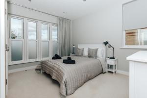 a white bedroom with a large bed and windows at Blue Heron - 2 Bedroom Apt with 2 parking spaces in Lower Assendon