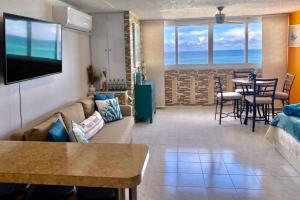 a living room with a couch and a television on a wall at KASA Emmas Ocean View in San Juan