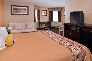 a hotel room with a bed and a flat screen tv at Americas Best Value Inn & Suites Madera in Madera