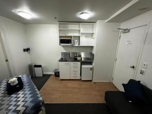 a small room with a bed and a kitchen at Columbia Apartments in Auckland