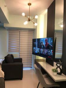 a living room with a large television and a table at MOA Pasay, Shore 3 Residences - Modern Luxury Condo in Manila