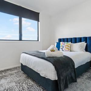 a bedroom with a large bed with a large window at Roomie Apartment Hotel in Auckland