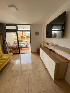 ein Wohnzimmer mit einem Sofa und einem TV an der Wand in der Unterkunft Apartament Modern 1 Playa del Ingles in San Bartolomé de Tirajana