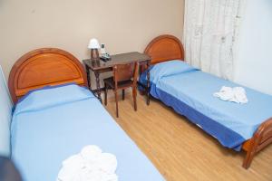 um quarto com 2 camas e uma secretária com uma mesa em hotel py jaguarão em Jaguarão