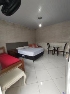 a bedroom with a bed and a table and chairs at Bertioga litoral in Bertioga