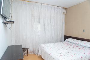 um quarto com uma cama e uma janela com cortinas brancas em hotel py jaguarão em Jaguarão