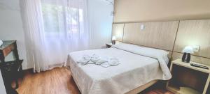 a bedroom with a bed with white sheets and a window at hotel py jaguarão in Jaguarão