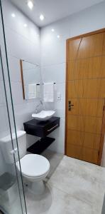 Suítes do Cabo في أرايال دو كابو: حمام مع مرحاض ومغسلة وباب خشبي