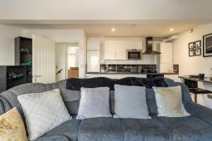 a living room with a gray couch and a kitchen at Cosy Brand new spacious 1 bed luxury apartment in Birmingham