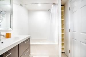 uma casa de banho branca com um chuveiro e um lavatório. em Spacious 1BR Suite just minutes from High Park em Toronto