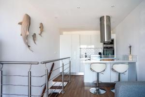 uma cozinha com armários brancos e um balcão com bancos em Cabanon avec terrasse - bord de plage - Le Cabanon 12 em Marselha