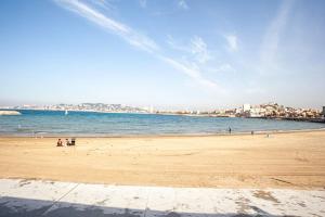 a beach with people on the sand and the water at Cabanon avec terrasse - bord de plage - Le Cabanon 12 in Marseille