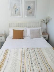 a bedroom with a white bed with two pillows at Salt Yard Apartment, Parking and Terrace, Whitstable in Whitstable