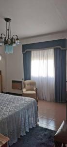 ein Schlafzimmer mit einem Bett, einem Stuhl und einem Fenster in der Unterkunft Vivenda Miraflores in Armação de Pêra