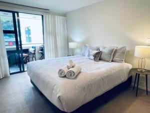 a bedroom with a large bed with towels on it at Oceanside Apartment in Mount Maunganui +14 photos