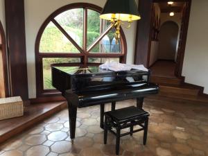 a black piano in a room with a window at Hotel Pousada Bella Locanda in Campos do Jordão