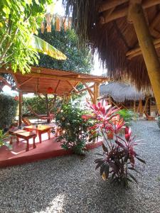 eine Terrasse mit einem Strohschirm, Tischen und Pflanzen in der Unterkunft Coco Sänkala Hostel in Palomino