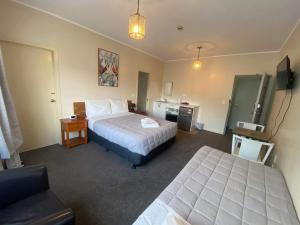 a hotel room with two beds and a chair at Airport Westney Lodge in Auckland