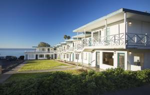 uma grande casa branca com o oceano ao fundo em Tides Oceanview Inn and Cottages em Pismo Beach