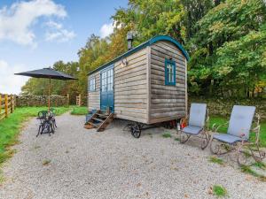 a small wooden cabin with two chairs and an umbrella at The Dalesbred Hut - Uk40150 in Rathmell