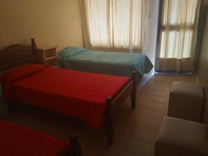Habitación pequeña con 2 camas y silla en Casa Marques en Santa Rosa