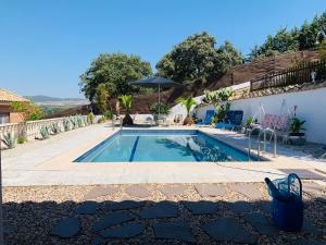 a swimming pool next to a house with an umbrella at JARAMUNDI in Villa del Prado
