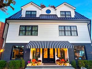 a white house with a black and white front door at The Menhaden Hotel in Greenport